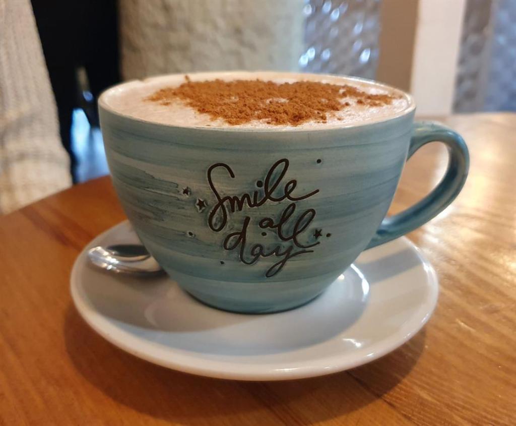 Tasse mit Cappuccino und der Aufschrift "Smile all day"